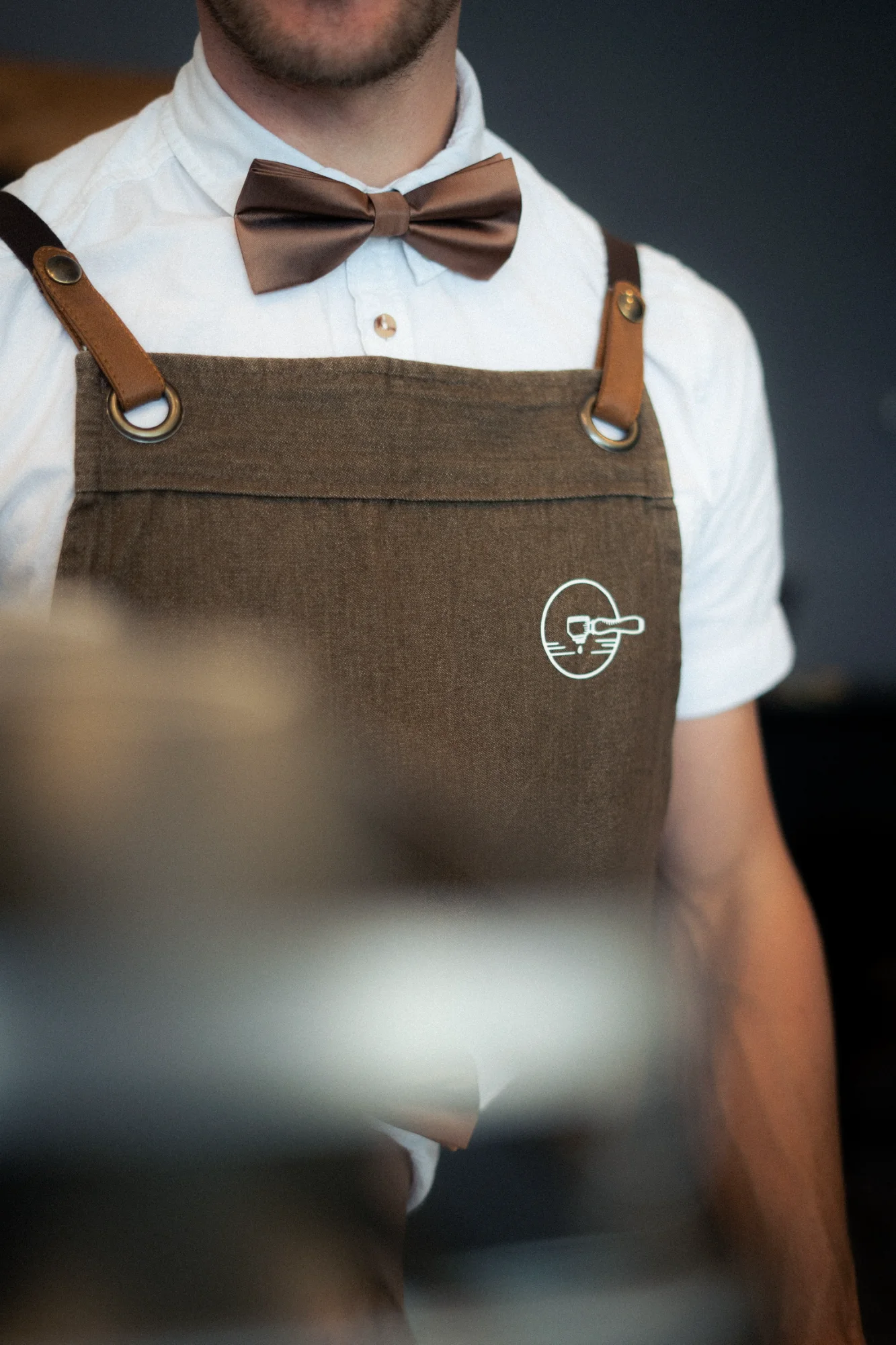 Barista mit brauner Schürze und Fliege