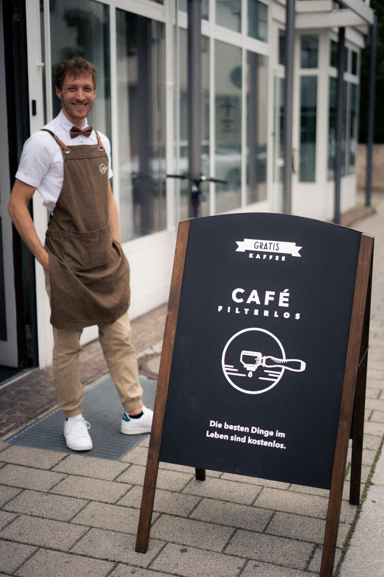 Barista vor dem Café mit Aufsteller